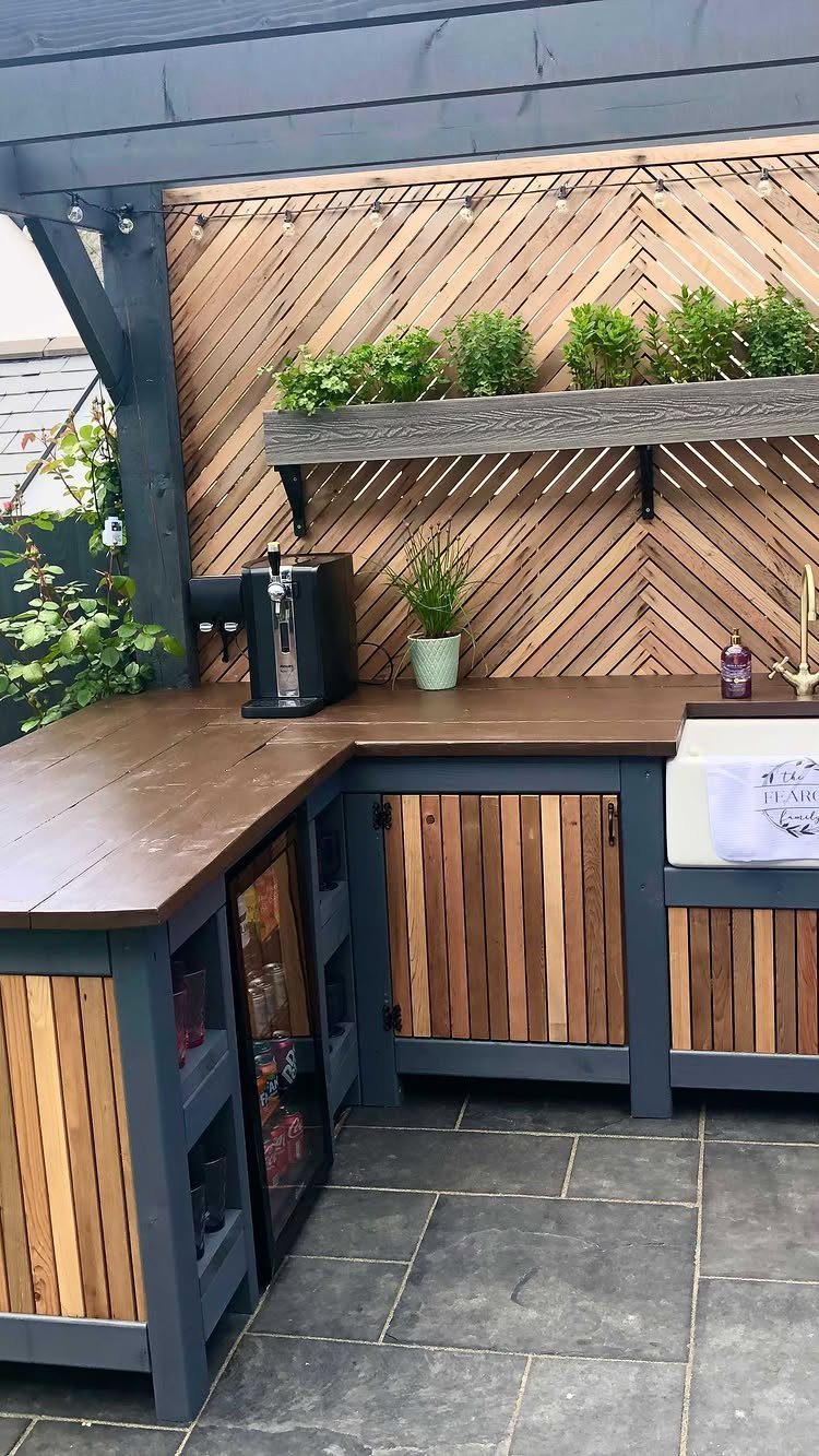 L-shaped outdoor bar with wood countertops, beverage cooler, and a wooden lattice backdrop.