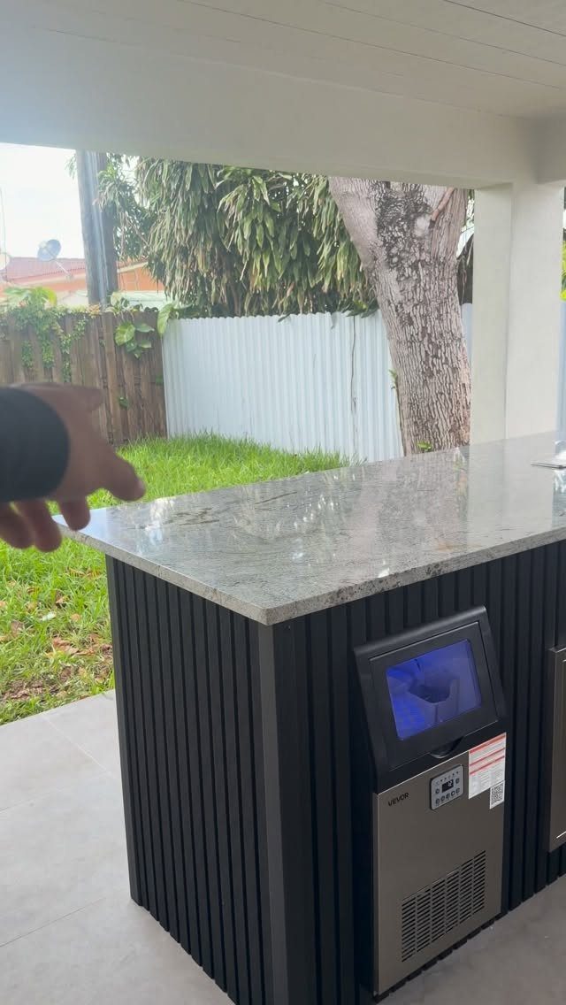 Outdoor bar with white granite countertop and built-in ice maker on a patio
