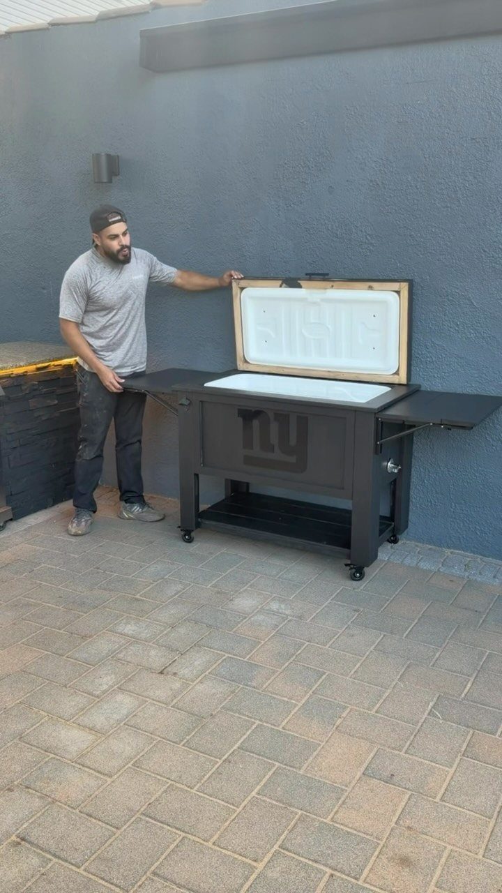 Man standing by a black mobile outdoor cooler bar on a paved patio