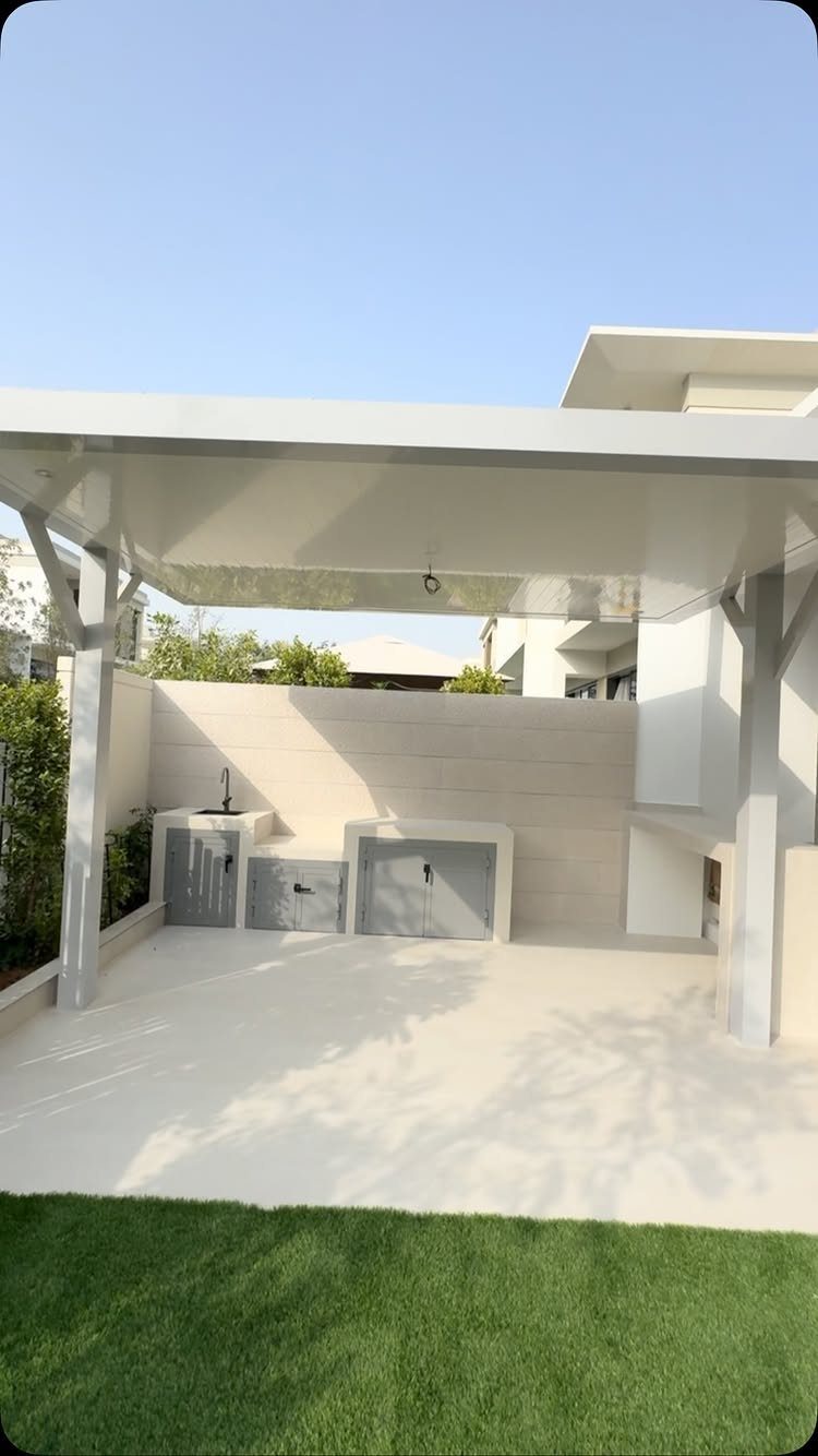 Outdoor kitchen with grey cabinets and a small sink under a white patio cover