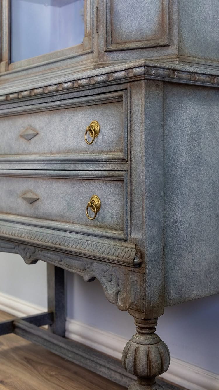 Weathered light blue painted vintage cabinet with gold ring pulls and ornate carvings.