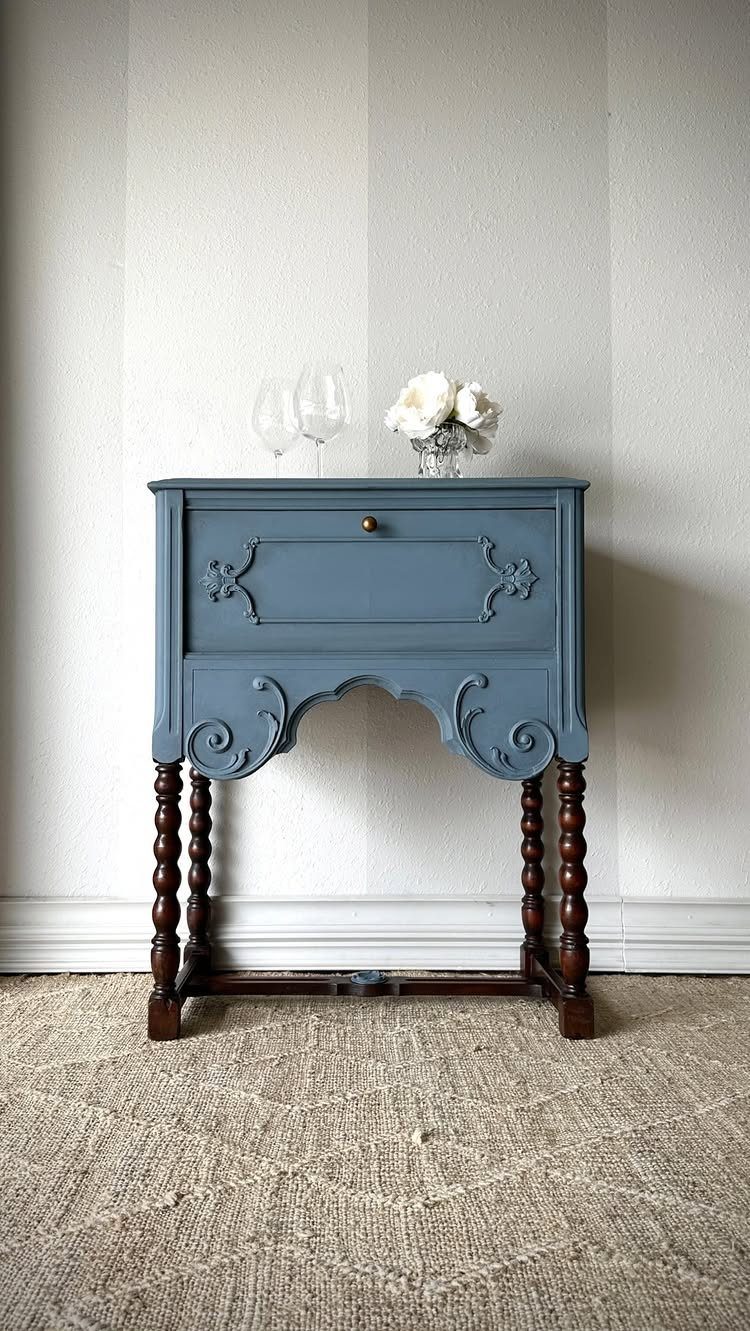 Blue painted wooden table with ornate carvings and dark brown turned legs.