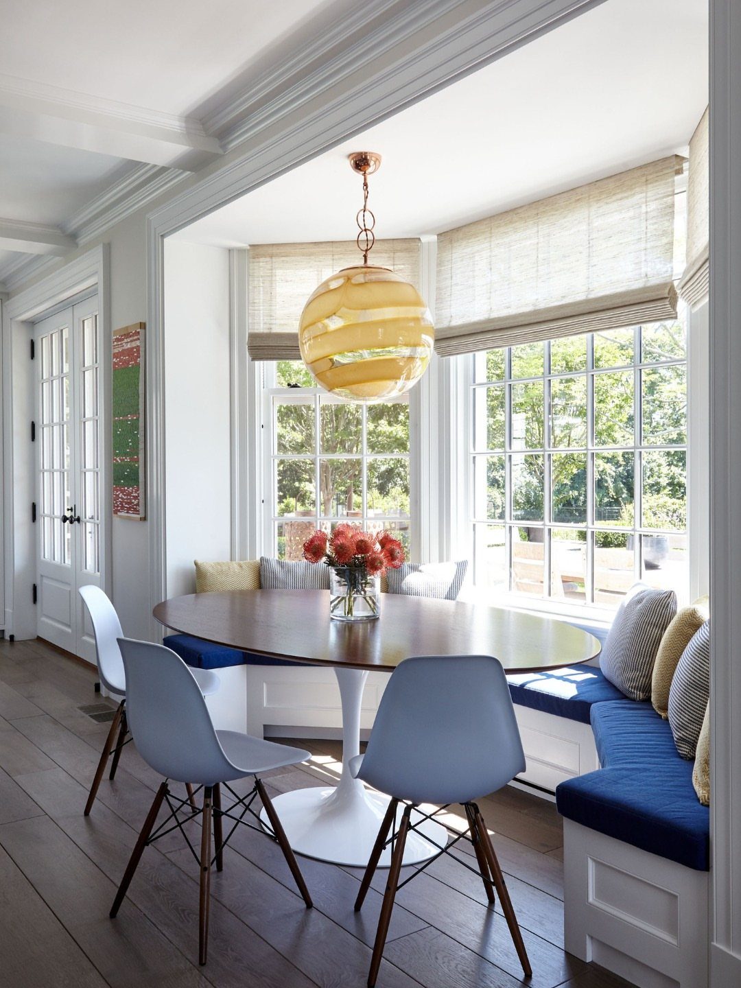 Breakfast nook with blue banquette seating and oval table in a bay window