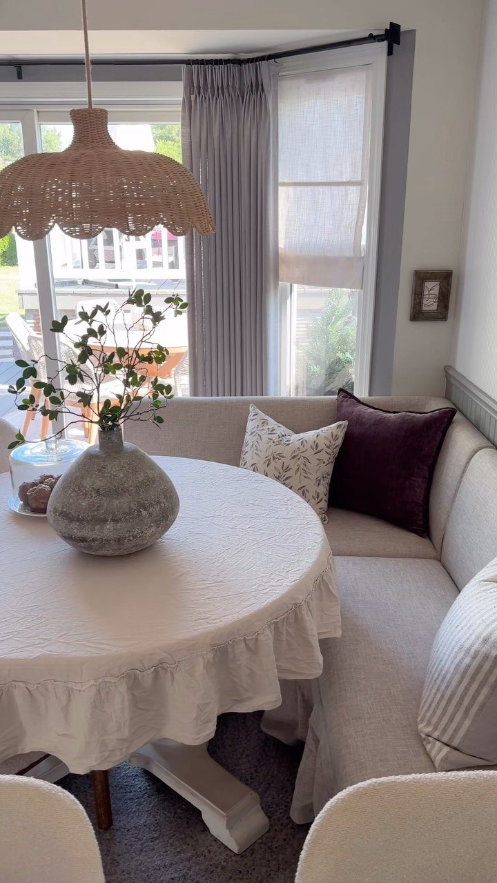 Round white table and curved beige banquette seating in a bright breakfast nook.