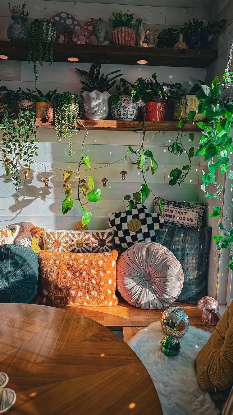 Cozy breakfast nook with colorful pillows, wooden shelves, and many indoor potted plants.