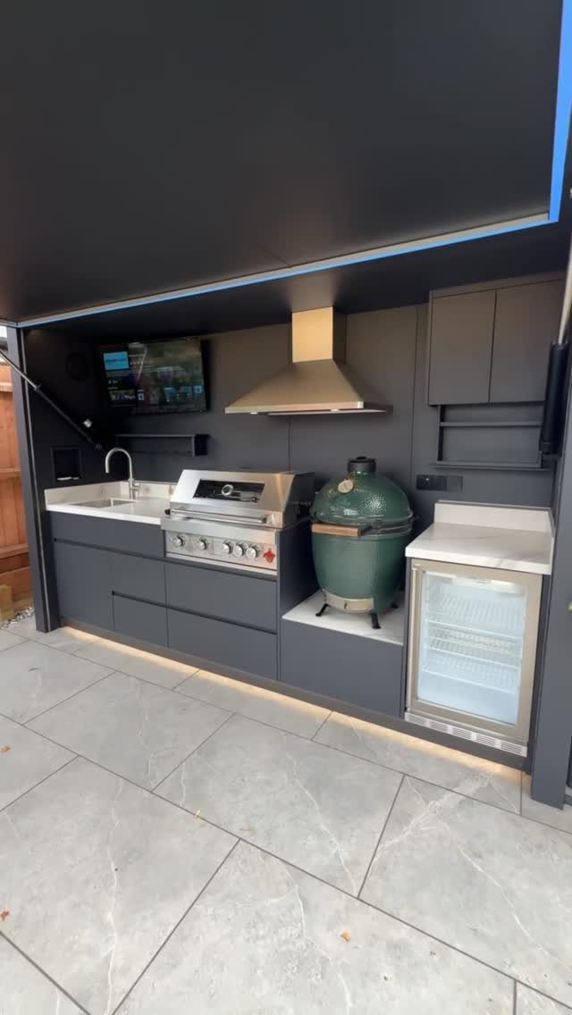 Modern outdoor grill station with dark grey cabinets, built-in grill, and ceramic cooker.