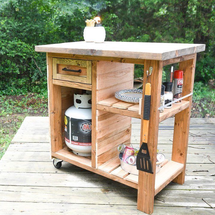 Wooden grill station with storage shelves, a drawer, and a propane tank on deck.