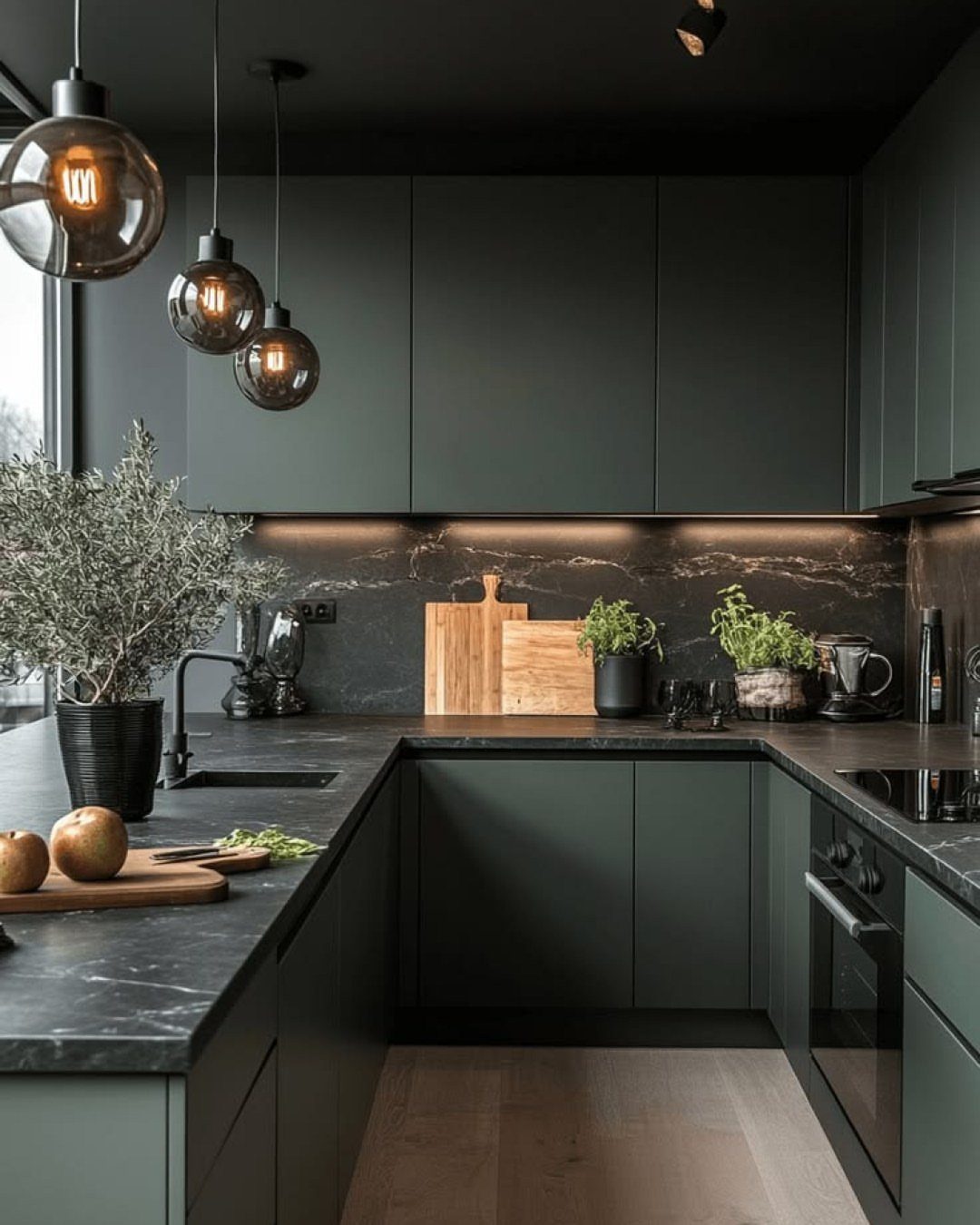 Charcoal gray kitchen cabinets with black marble countertops and glass globe pendant lights.