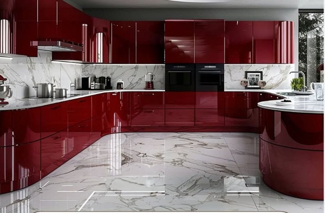 Glossy red kitchen cabinets with white marble countertops and matching marble flooring.