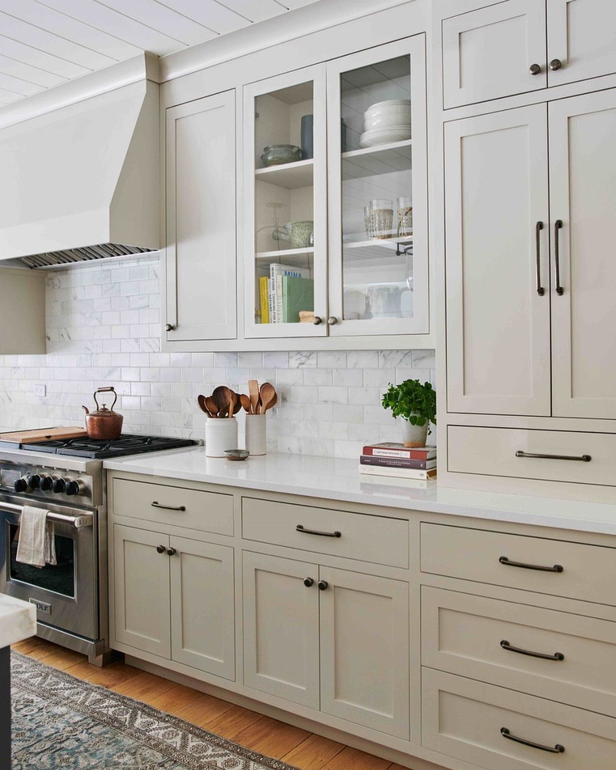 Greige shaker-style kitchen cabinets with white countertops and a white subway tile backsplash.