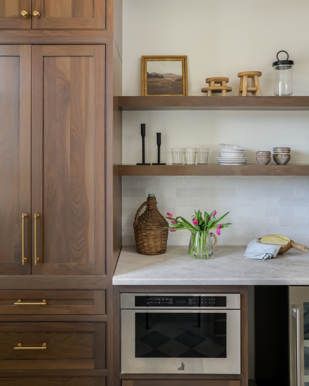 Brown wood cabinets and open shelving paired with white marble countertops and gold hardware.