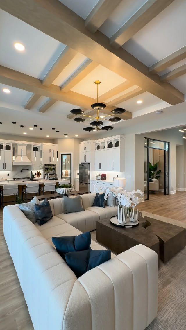 Modern open-concept living space with a white kitchen and large white sectional sofa.