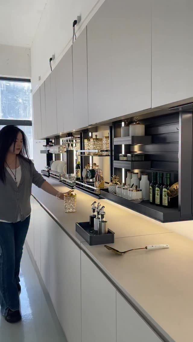 Woman standing in a modern white kitchen with a recessed black shelving unit.