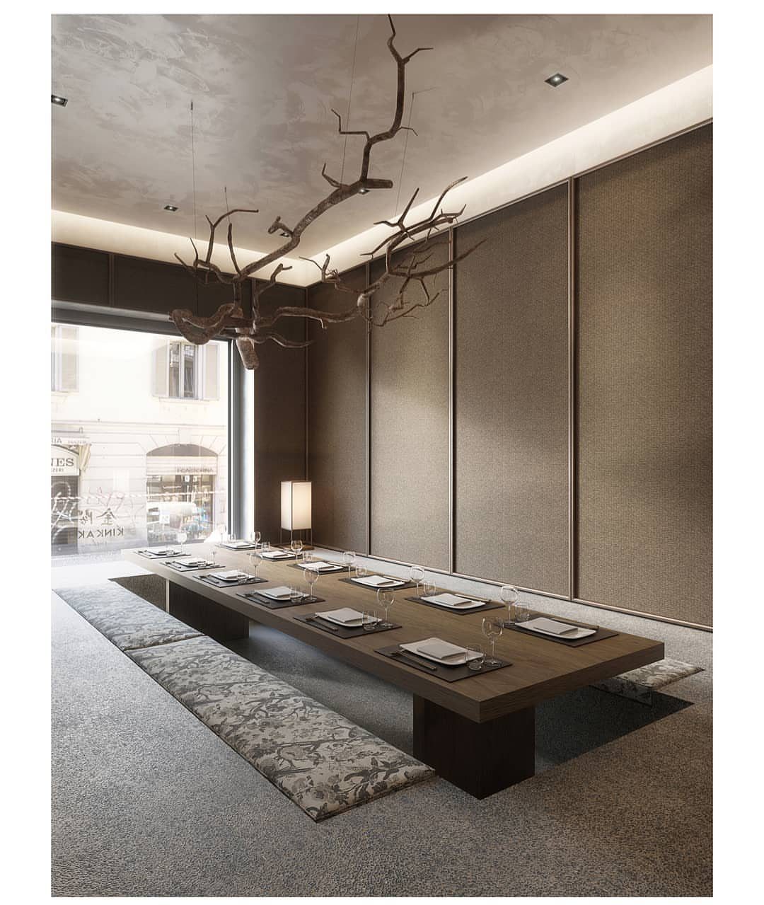 Low wooden dining table in a minimalist Japanese room with branch ceiling art