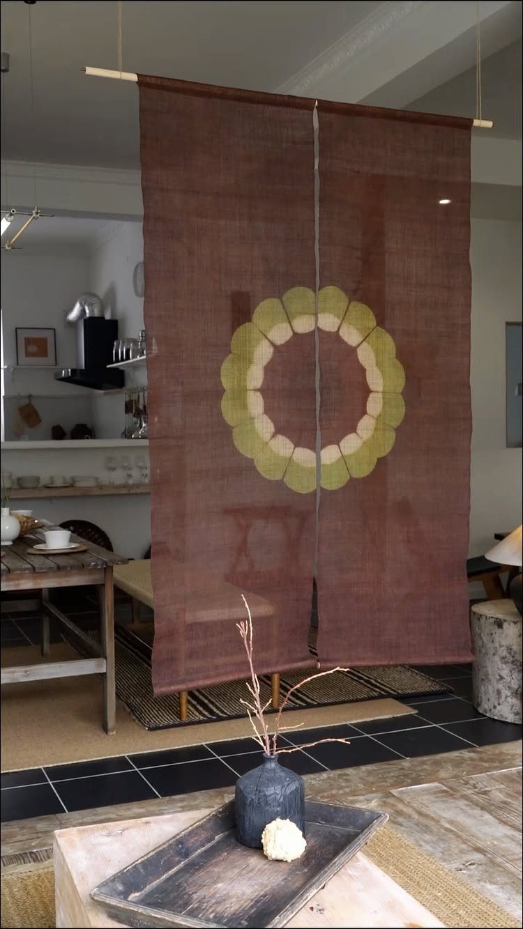 Brown noren curtain with a circular floral design dividing a Japanese style room