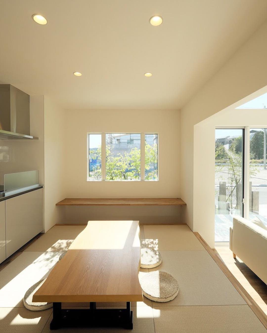 Wooden dining table and floor cushions on woven tatami mats in a bright room