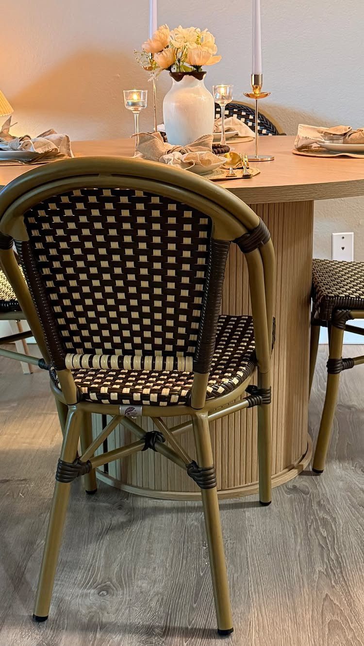 Woven rattan chair with checkered pattern next to a round wooden dining table.