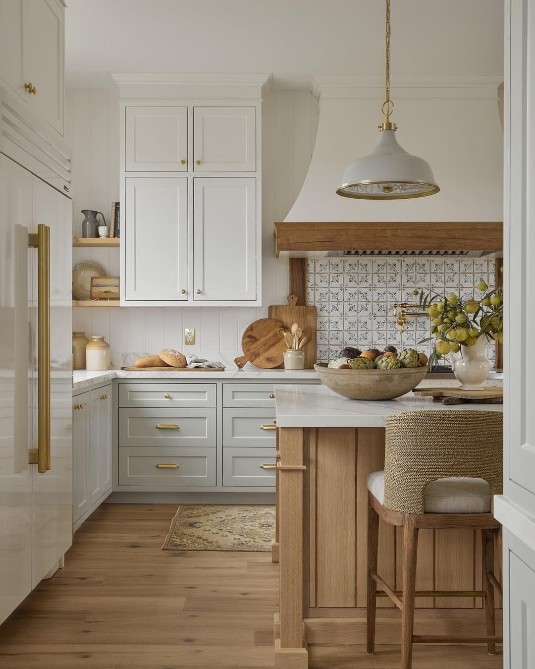 White and grey traditional cabinetry in a bright farmhouse kitchen with wooden island.