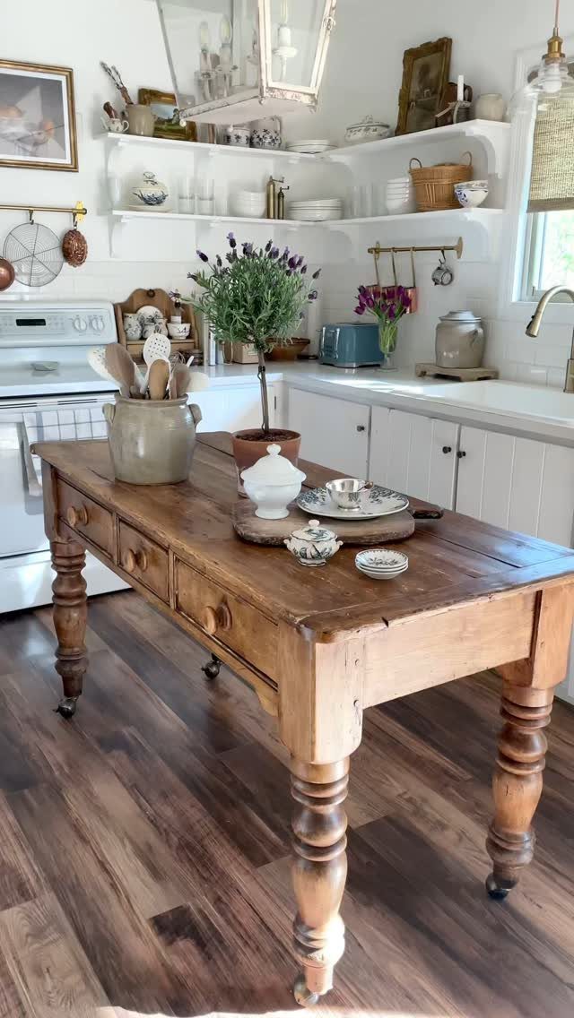 Rustic wooden kitchen island with turned legs and drawers in a white kitchen