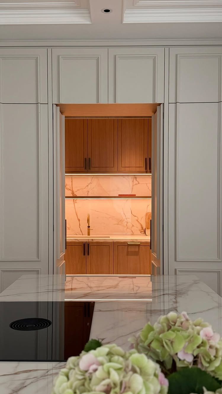 Concealed appliance cupboard with pocket doors revealing a wood interior and marble backsplash.