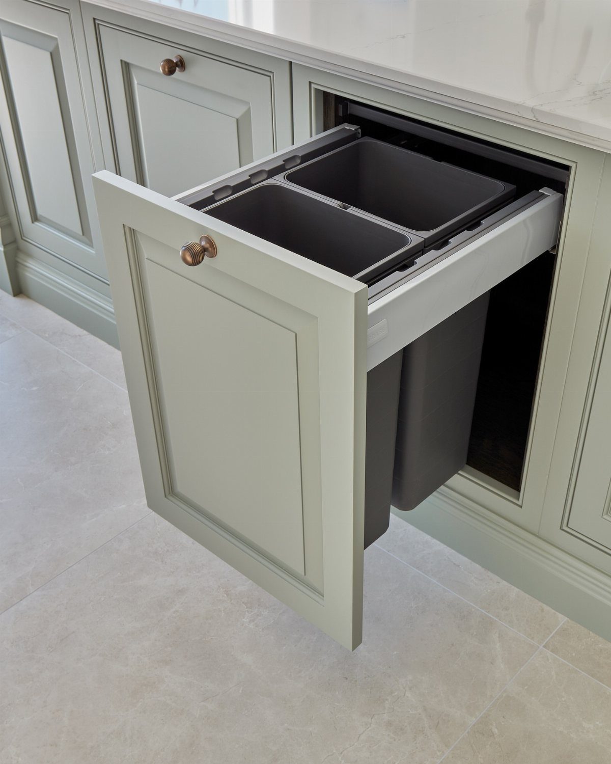 Pull-out kitchen cabinet drawer containing two grey trash and recycling bins.