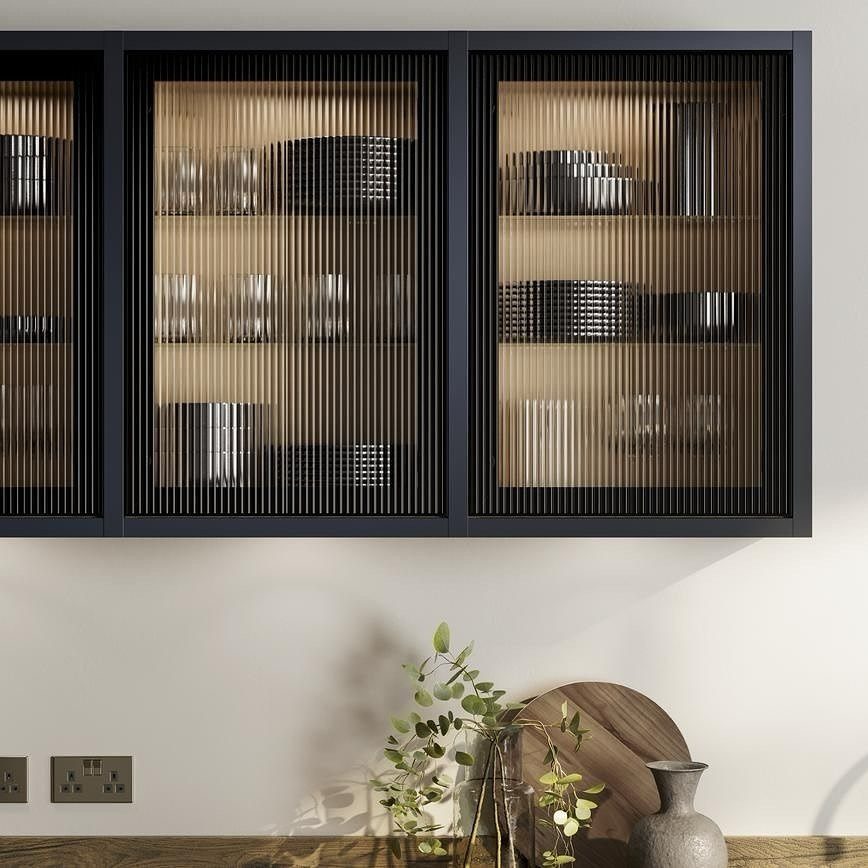 Black kitchen cabinets with fluted glass doors and interior lighting over a wooden counter