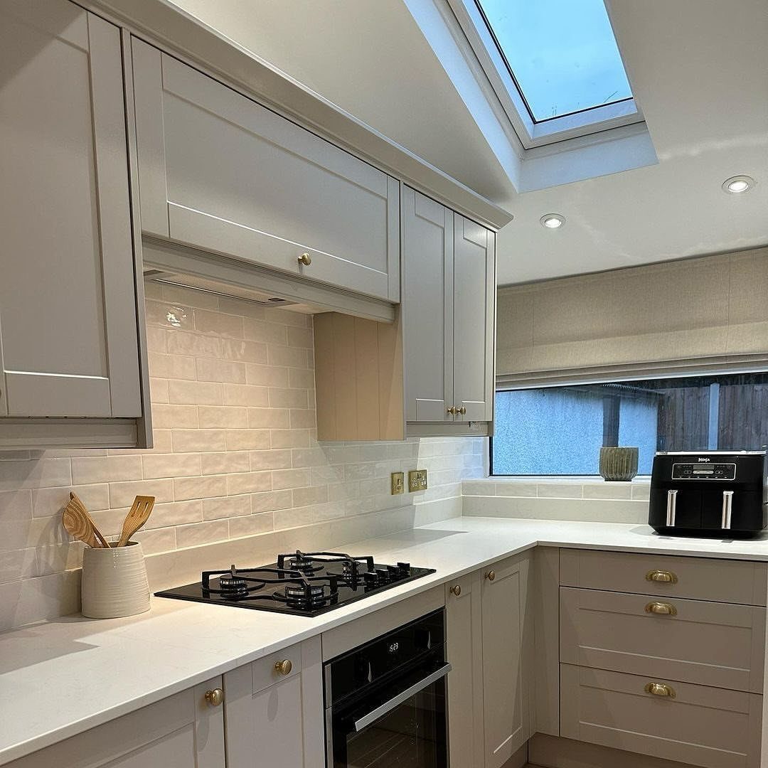Creamy white tiled backsplash in a modern kitchen with light grey cabinets.