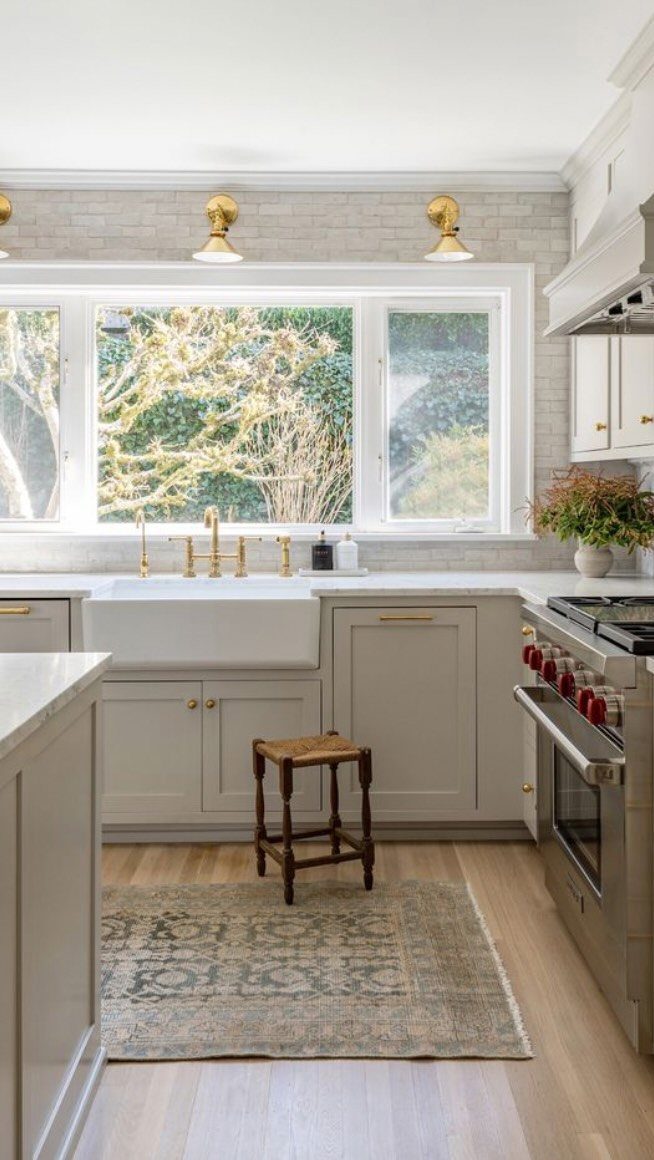 Warm beige kitchen cabinets with a white farmhouse sink and gold hardware accents.