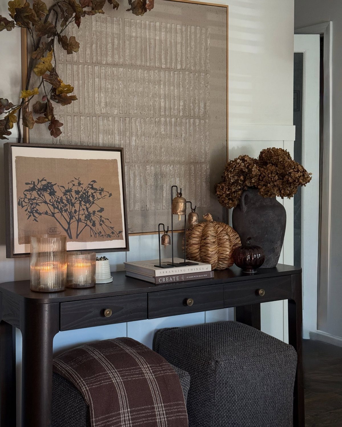 Dark wood console table with books, a dark vase, and framed wall art.