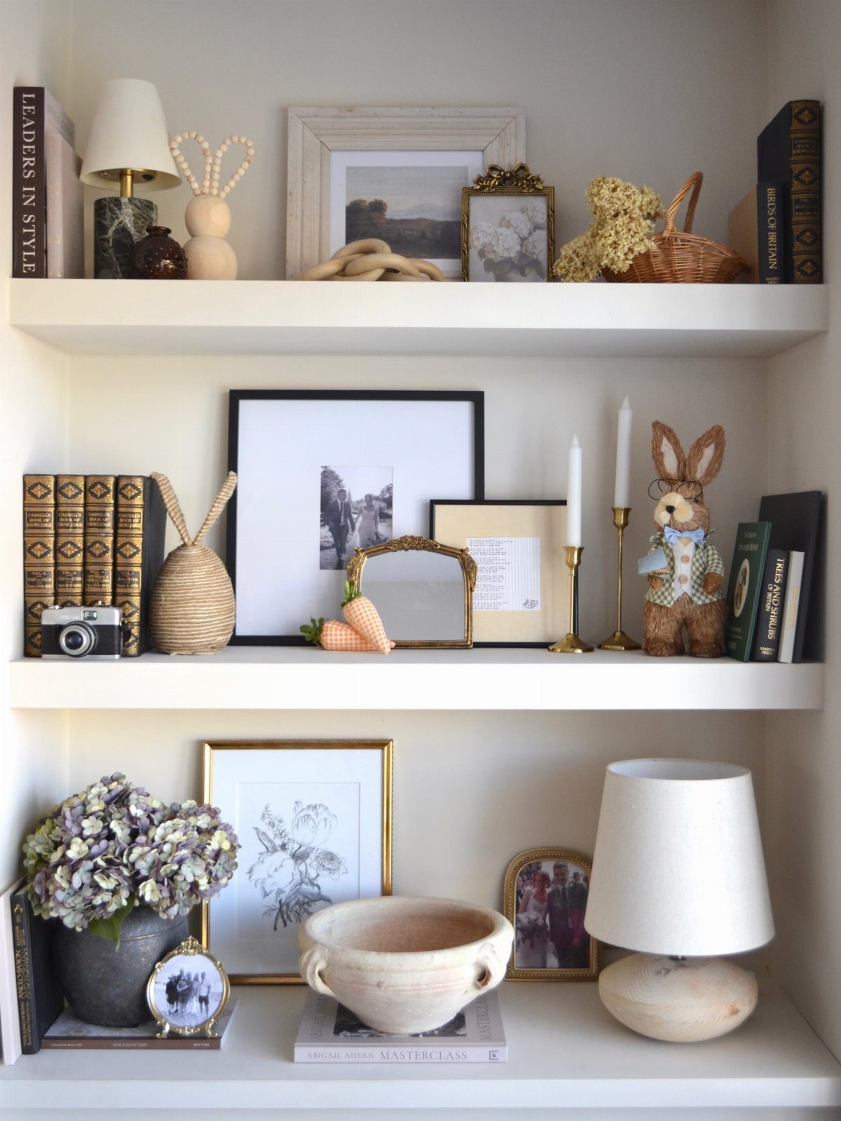 White floating shelves decorated with framed art, books, lamps, and neutral home accessories.