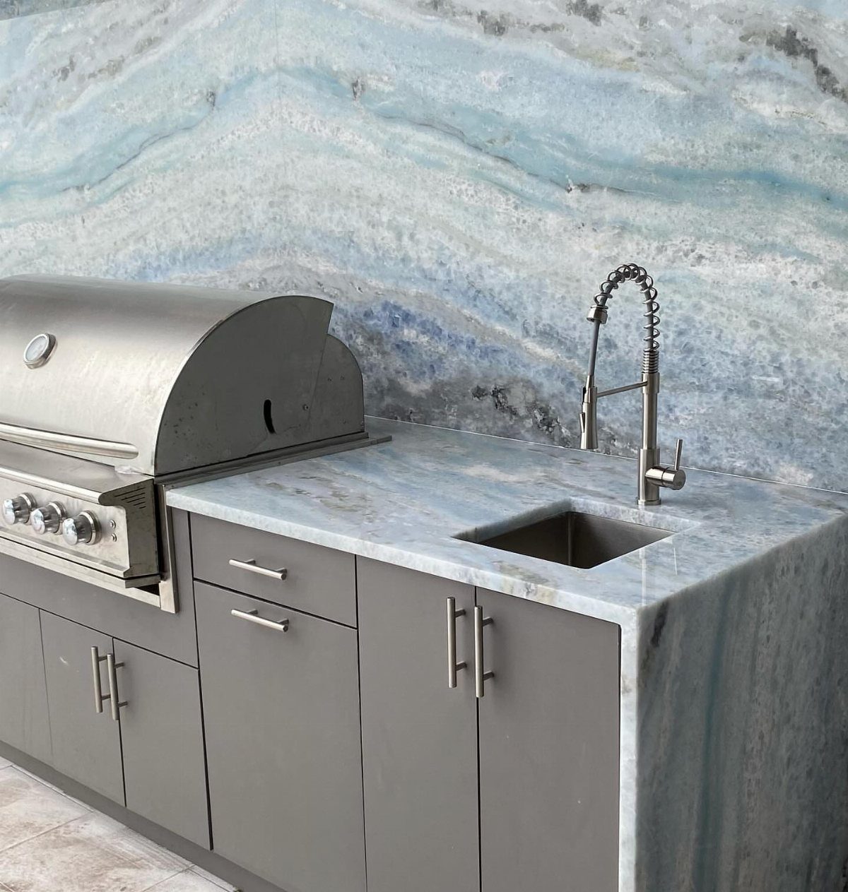 Blue and white veined natural stone backsplash and countertop in outdoor kitchen