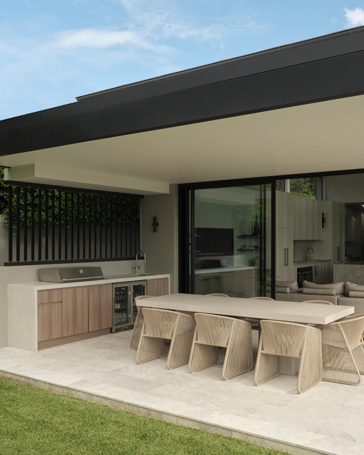Minimalist outdoor kitchen with light countertops, wooden cabinets, and a dining area.