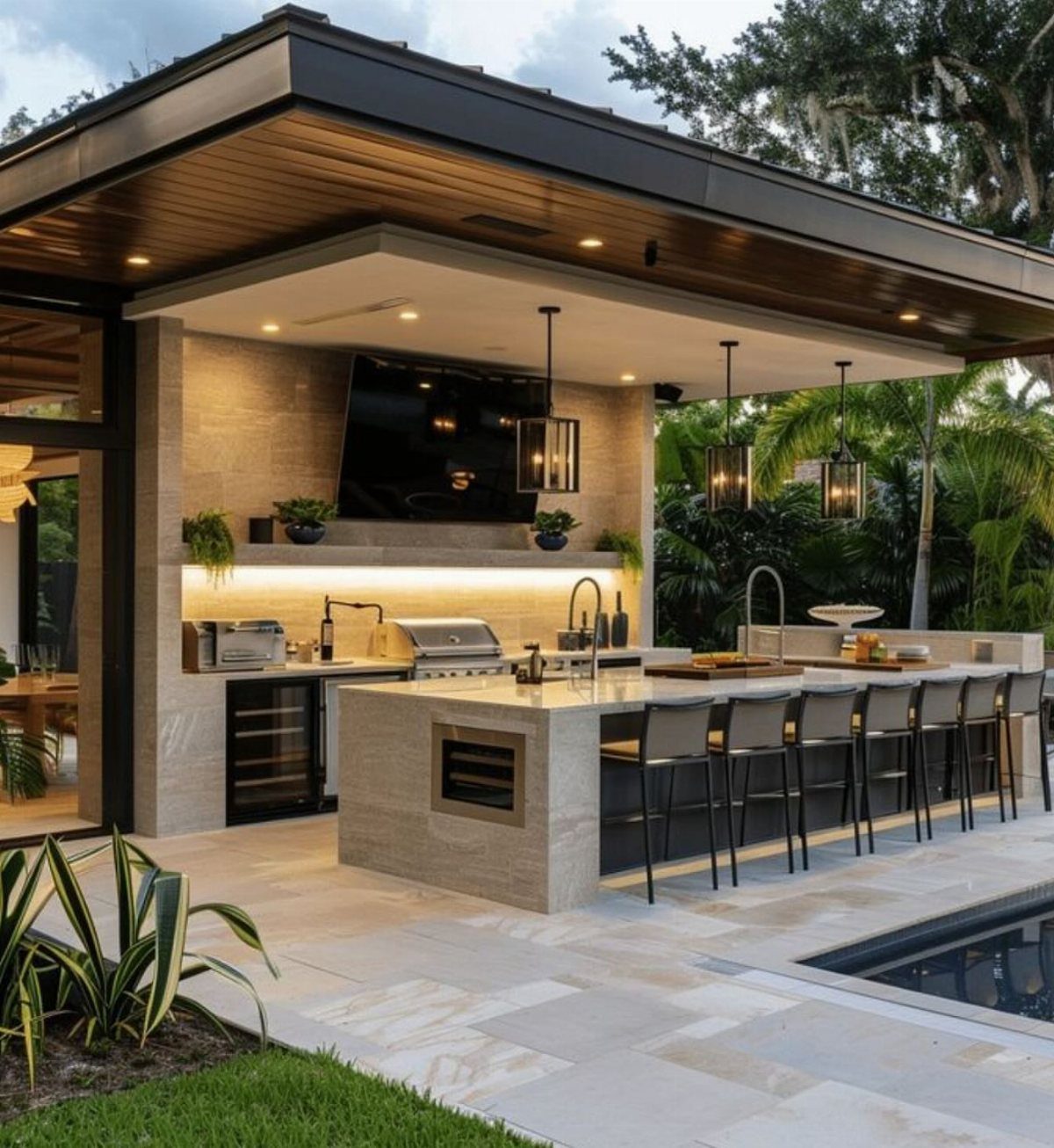 Modern outdoor kitchen featuring black pendant lights hanging over a stone island counter.