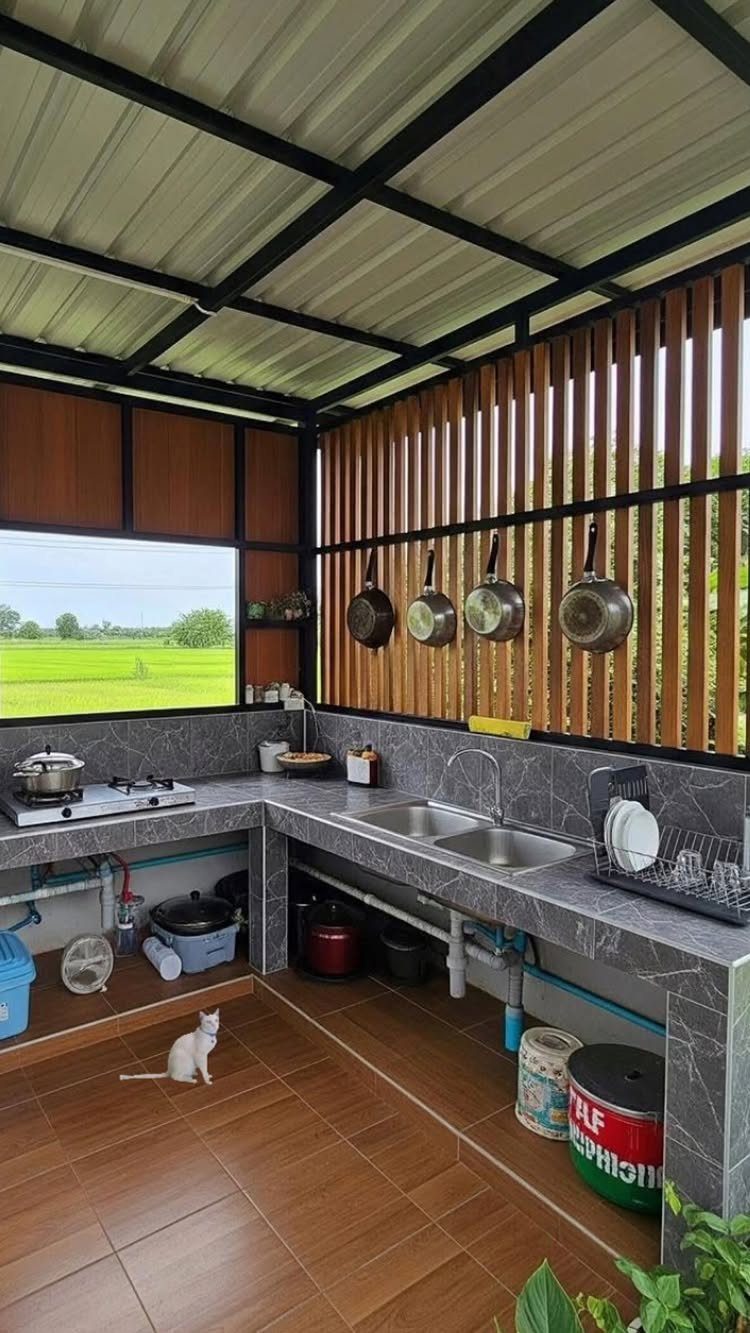 Outdoor kitchen with grey marble counters, wooden slat walls, and a white cat.