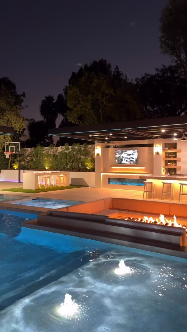 Luxury backyard with a swimming pool, sunken fire pit, and outdoor kitchen area.
