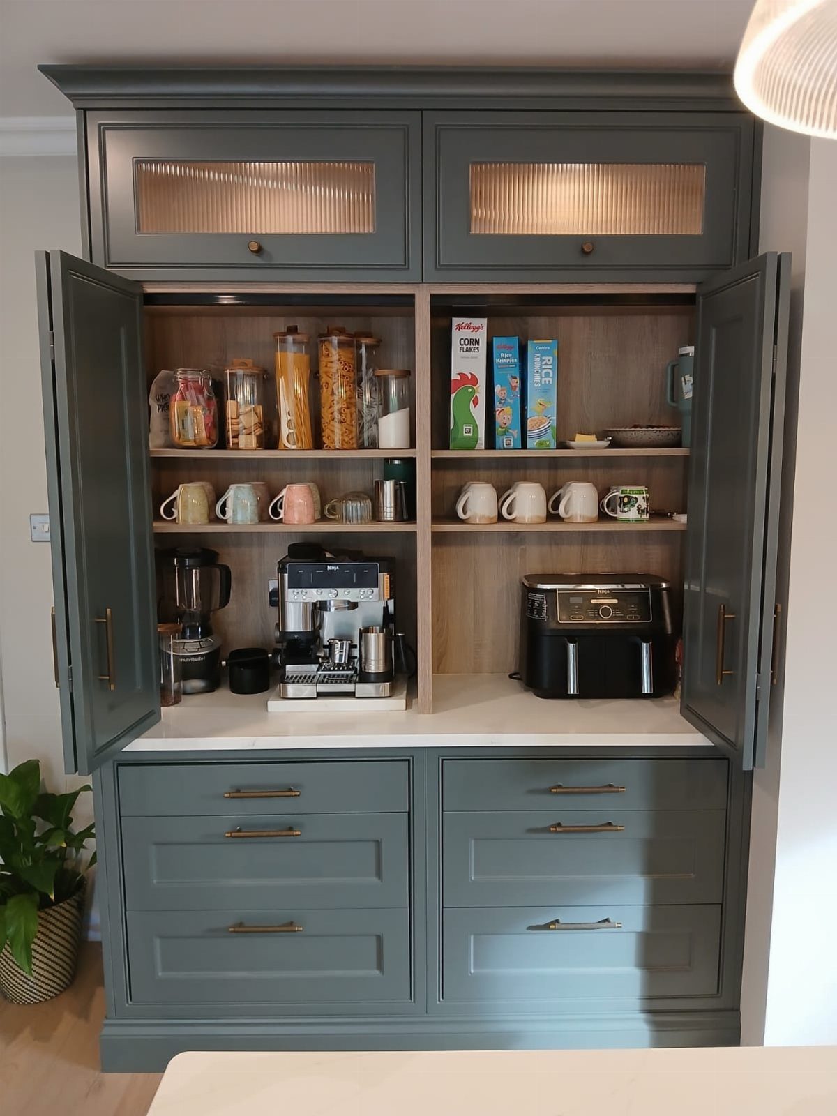 Grey kitchen pantry cabinet with open doors showing coffee station and organized shelves
