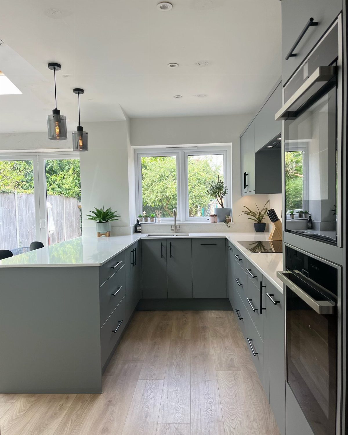 Grey kitchen with a white countertop peninsula and light wood floors.